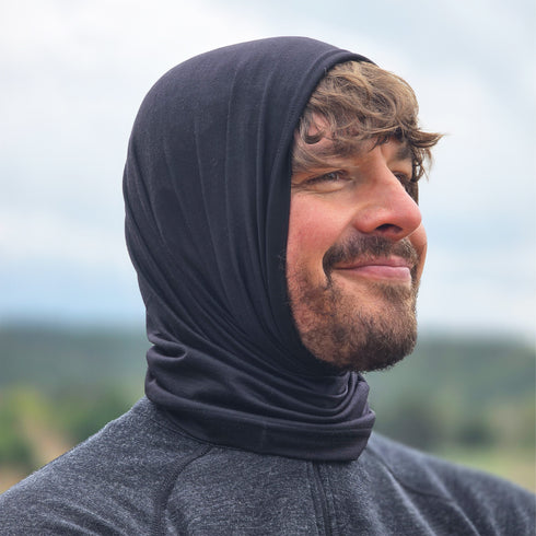 Mann trägt einen schwarzen Merino Multifunktionstuch über dem Kopf