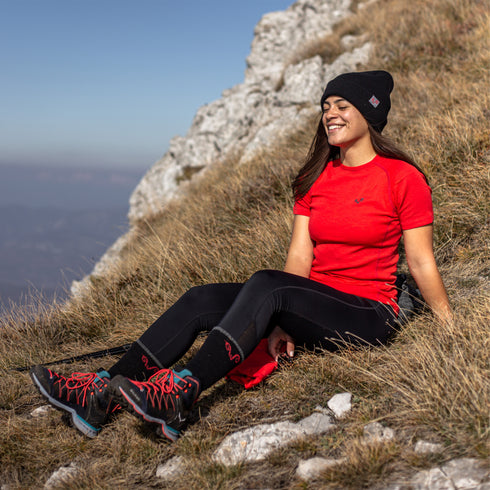 Eine Frau sitzt auf einer Wiese und trägt ein Rotes Merino-T-Shirt