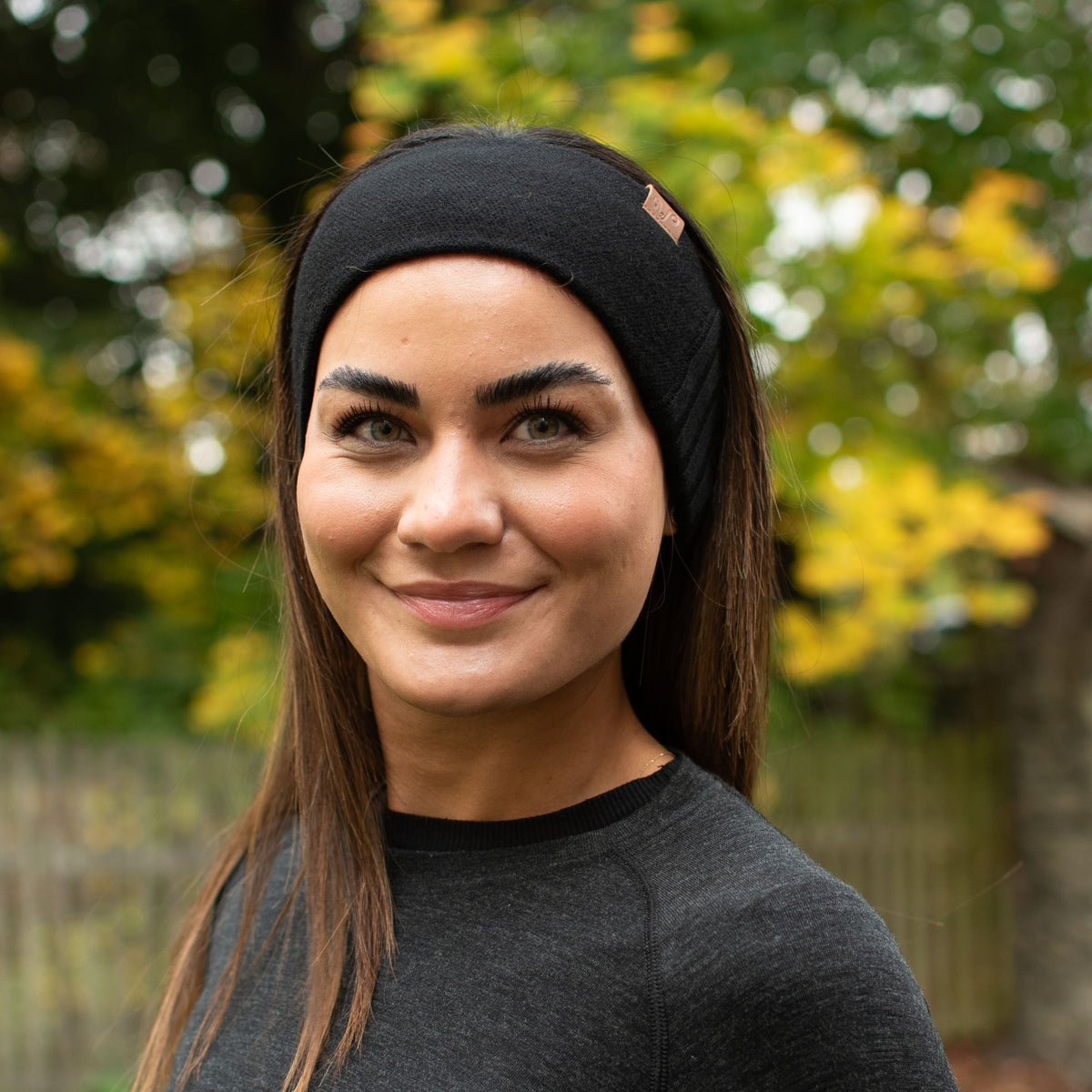 Eine Frau mit einem schwarzen Stirnband aus 100% Merinowolle in der Natur.