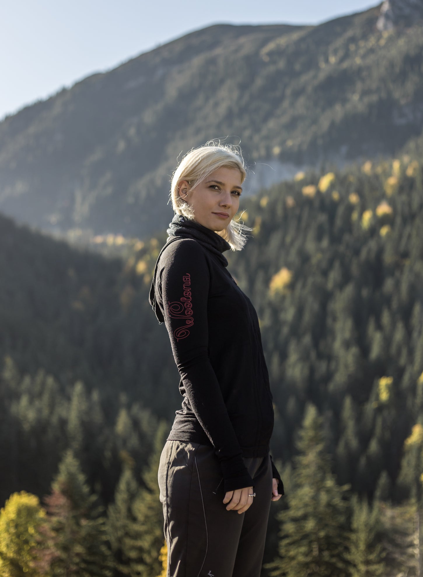 Frau mit Merino-Funktionskleidung steht in einem bergigen Waldgebiet