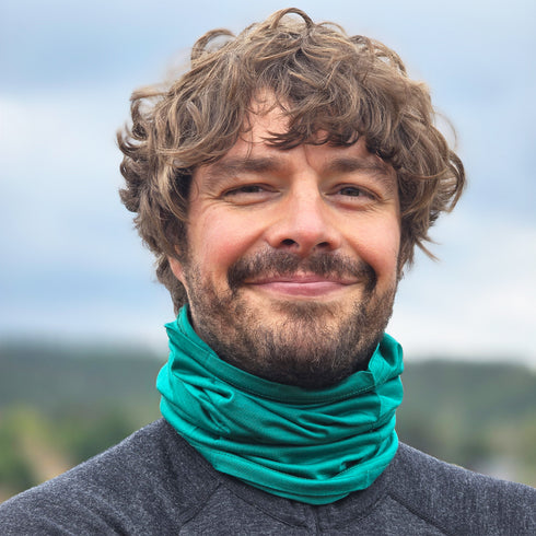 Ein Mann in Merinobekleidung aus nachhaltiger Herkunft trägt Multifunktionstuch aus Merinowolle