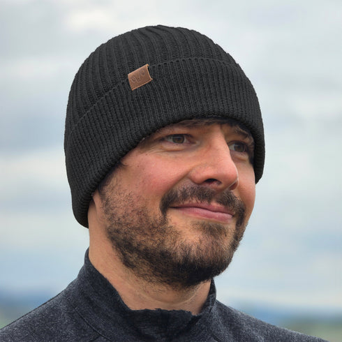 Mann trägt gestrickte Wintermütze aus 100% Merinowolle in Anthrazit.