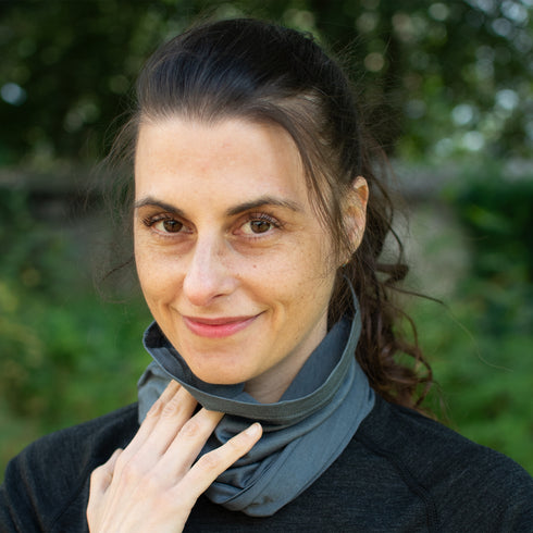 Frau hat grauen Nackenwärmer aus Merinowolle um den Hals.