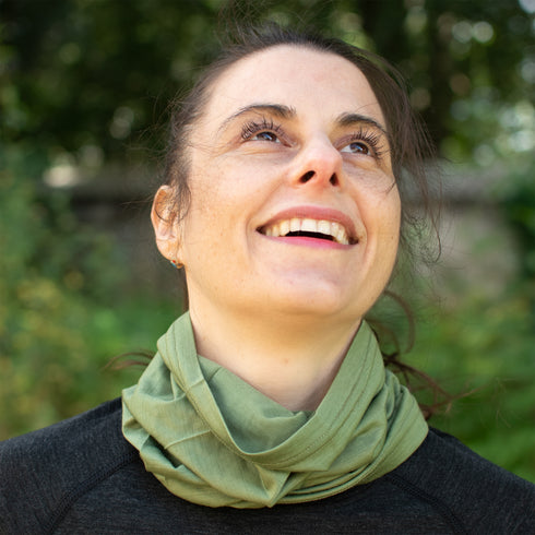 Eine lachende Frau trägt Merino Halswärmer aus 100% nachhaltigem Stoff