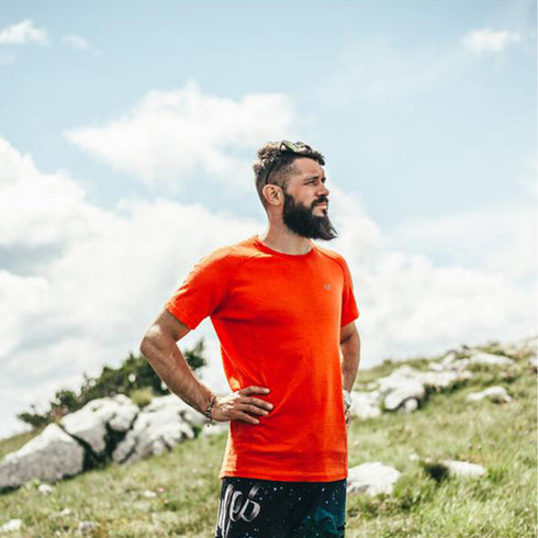 mann in den Bergen mit orangen merinowolle T-Shirt