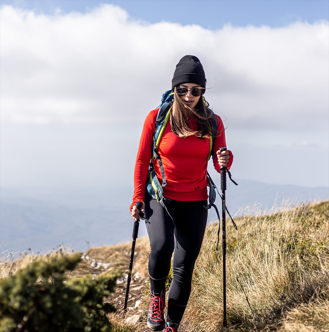 Frau beim Wandern mit einem roten Merino Oberteil