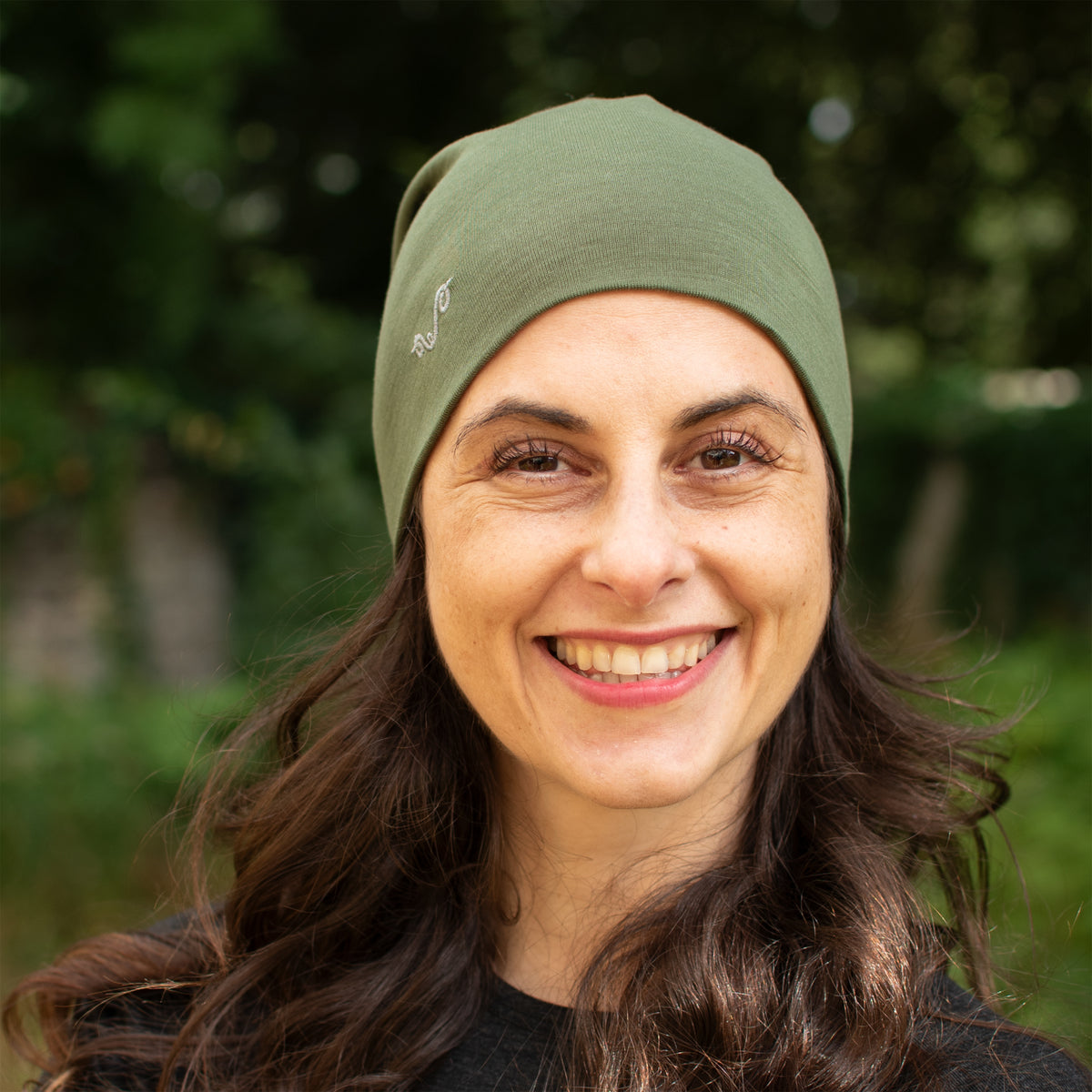 LĂ€chelnde Dame trĂ€gt olivgrĂŒnen Merinowolle Beanie