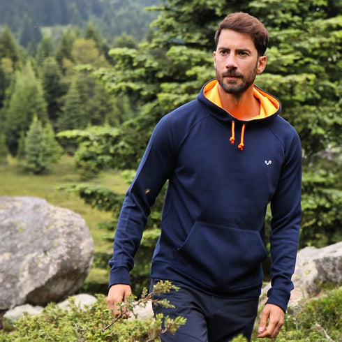 Ein Mann durchschreitet ein Waldstück und trägt einen Navy-Blauen Pullover aus 100% Merinowolle