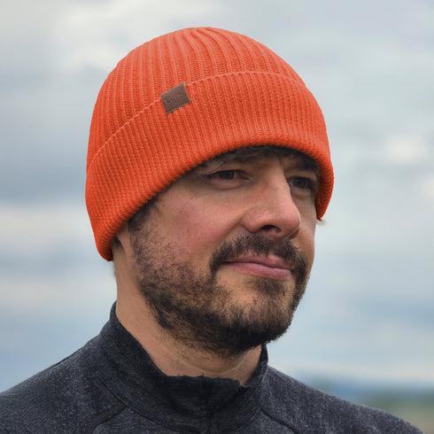 Mann trägt Orange-farbene Wintermütze aus 100% Merinowolle.