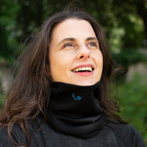 Eine Frau trägt einen schwarzen Merino Nackenwärmer in der Natur