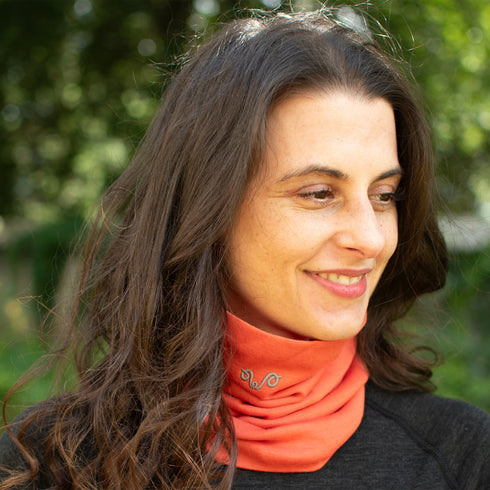 Frau trägt orangefarbenen Buff aus 100% Merinowolle