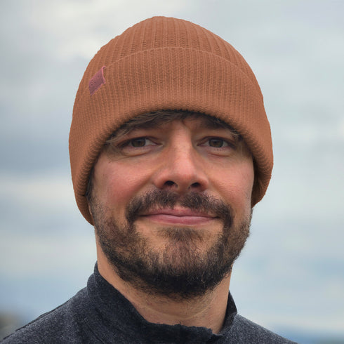 Mann trägt gestrickte Wintermütze aus 100% Merinowolle in der Farbe hellbraun.