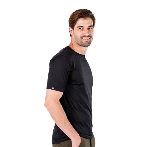 Mann von der Seite lächelt und trägt ein schwarzes Merinowolle T-Shirt