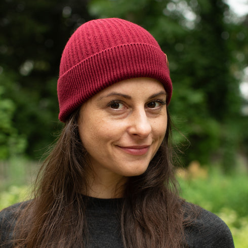Wanderer in Merinobekleidung trägt Bordeaux-rote Wintermütze.