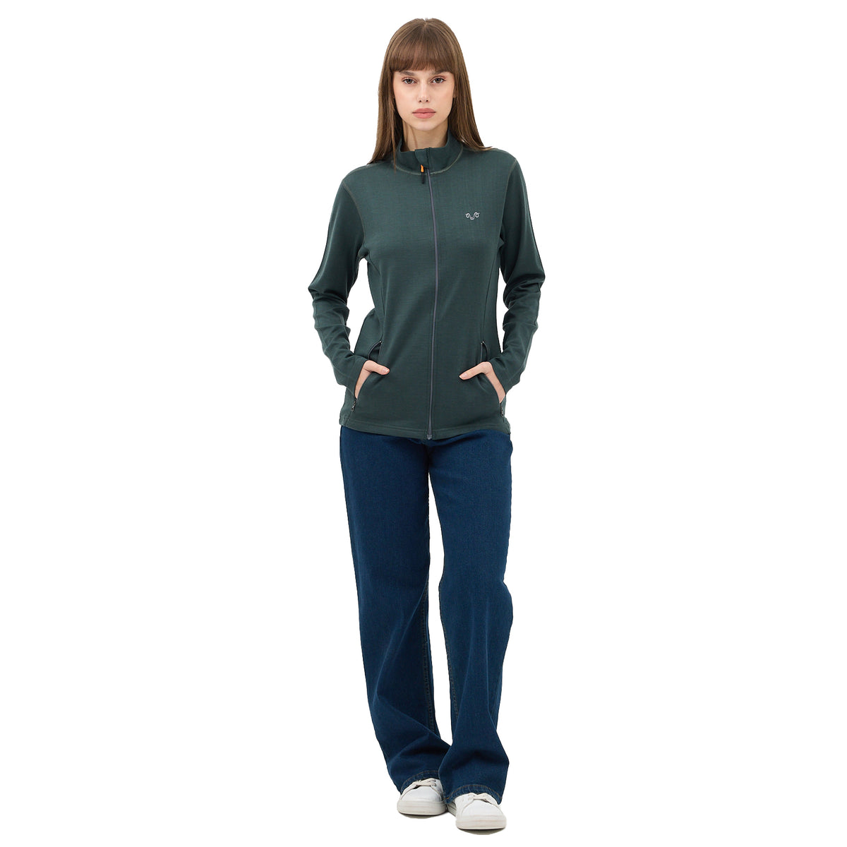 Frau mit langen braunen Haaren, trägt einen grünen Midlayer und blaue Jeans.