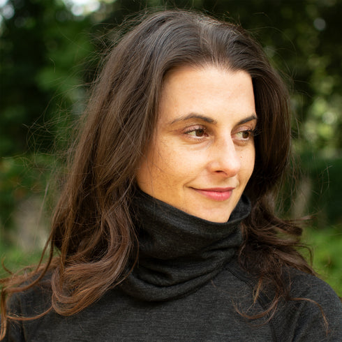 Frau trägt anthrazitfarbene Merinobekleidung und einen passenden Nackenwärmer aus 100% Merinowolle