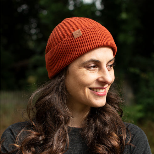 Frau lächelt und trägt Ziegelrote Strickmütze