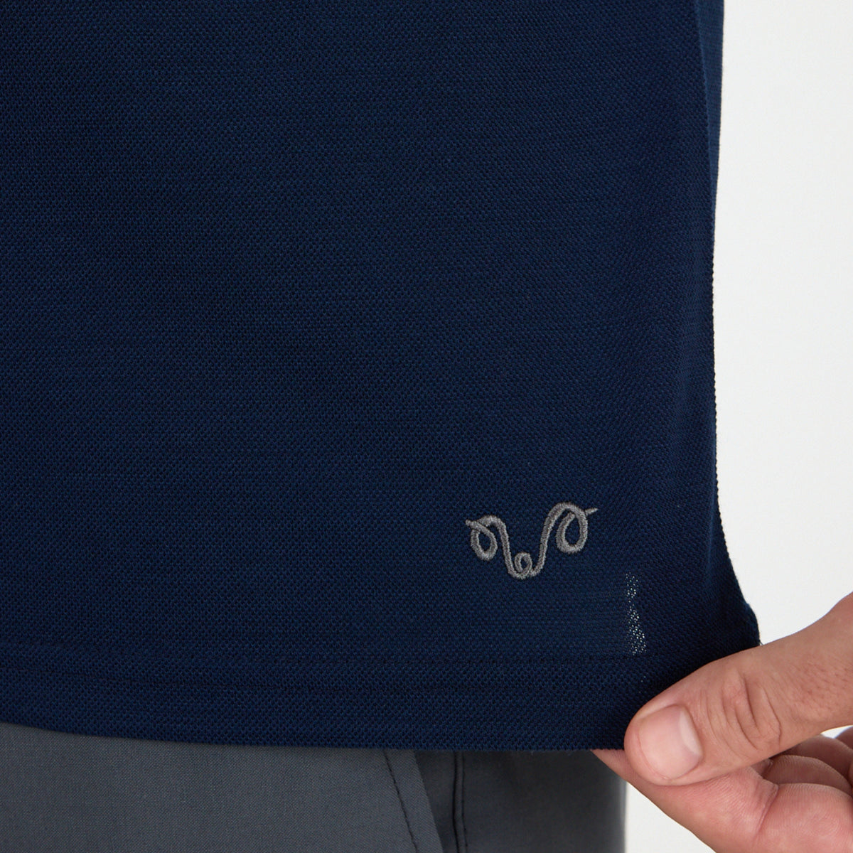 Merino Polo Shirt im Pique Style. Nahaufnahme im unteren Bereich mit grauem Logo.