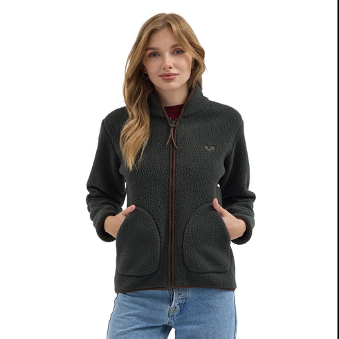 Das Model trägt eine grüne Sherpa Jacke mit Merino-Innenfutter und hat die Hände in den Jackentaschen.