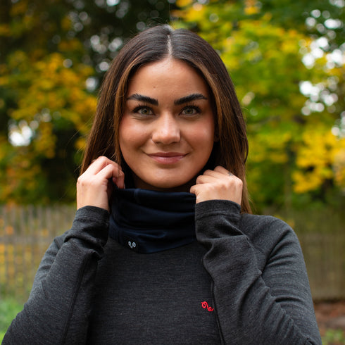 Die Dame trägt ein Merino-Oberteil und Nackenwärmer in Navy Blau aus 100% Merinowolle
