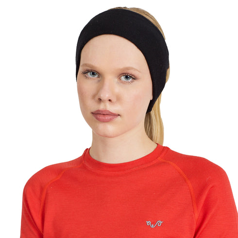 Eine Frau trägt ein schwarzes Stirnband aus Merinowolle und ein rotes Shirt ebenfalls aus Merinowolle.