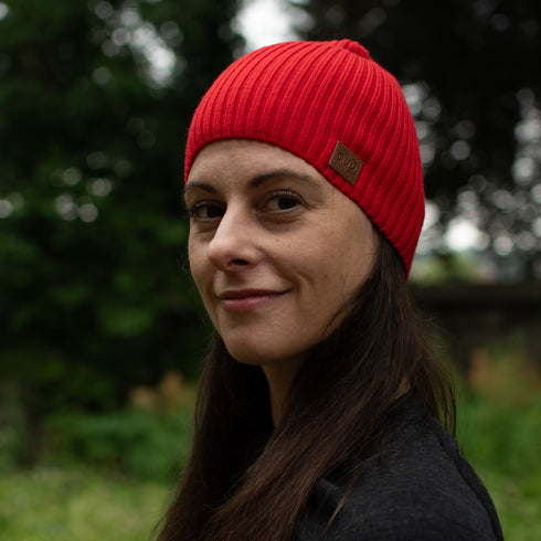 Eine Frau mit einer schönen roten Merinomütze und einem Logo von Woolona.