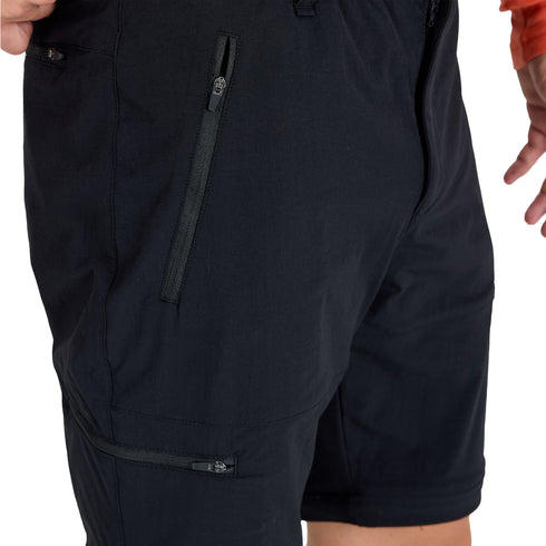 Mann in kurzer Variante der Zip-Off Merinohose mit Bein - und Hosentasche mit Reißverschlüssen.