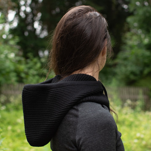 Die Wanderin trägt einen Kapuzenschal offen über den Schultern.