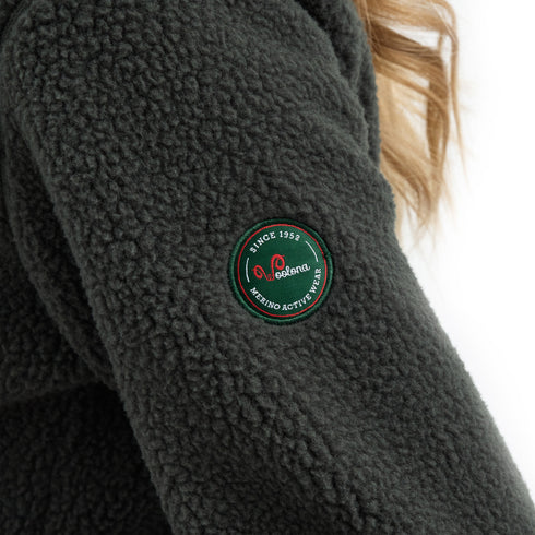 Grüne Sherpa Jacke mit Woolona Emblem am Ärmel.