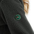 Grüne Sherpa Jacke mit Woolona Emblem am Ärmel.