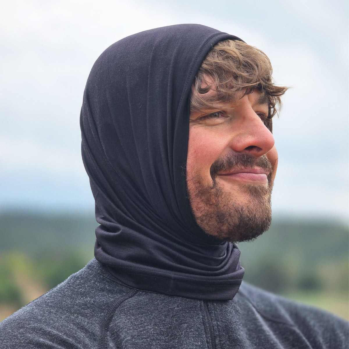 Mann trägt einen schwarzen Merino Multifunktionstuch über dem Kopf