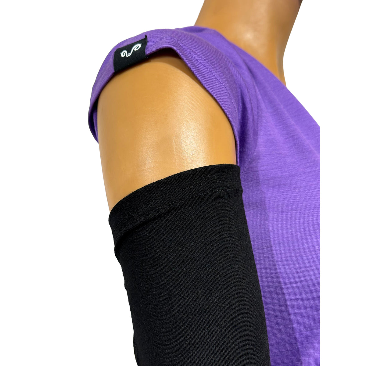 Ende eines Armwärmer in Schwarz aus Merinowolle, Dame trägt ein Merino Shirt in Lila mit Woolona Logo