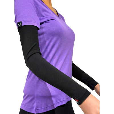 Armwärmer in Schwarz aus Merinowolle mit Woolona Logo an einer Dame mit lilanen Shirt