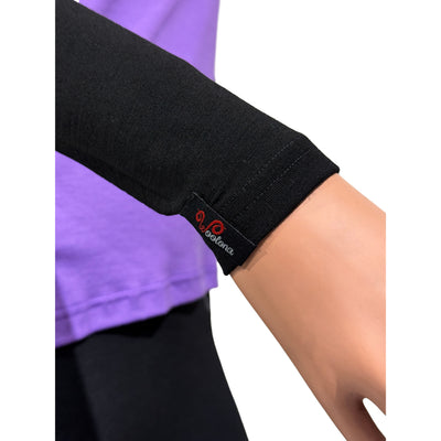 Aus der nähe das Woolona Logo am Armwärmer aus Merinowolle in Schwarz, getragen von einer Dame mit lilanem Shirt