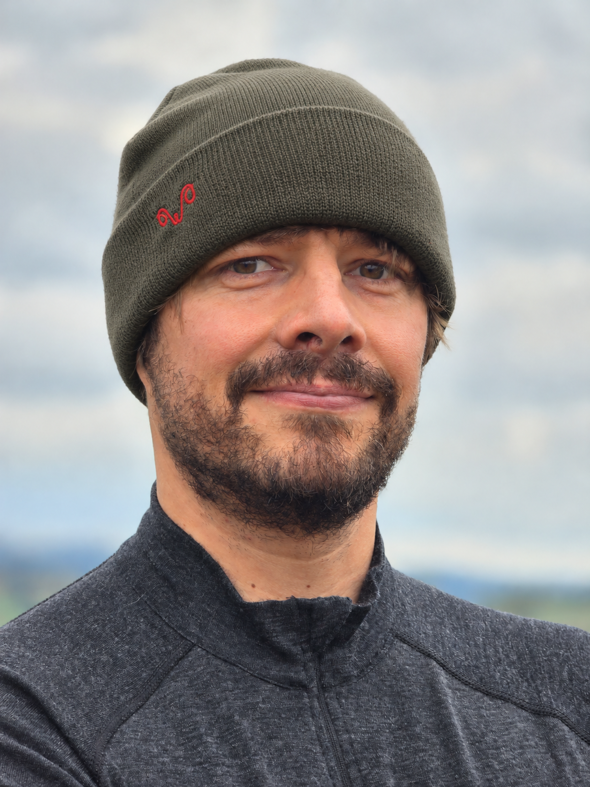 Mann mit grüner Merinomütze mit rotem Woolona Logo