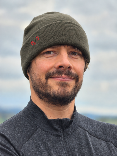 Mann mit grüner Merinomütze mit rotem Woolona Logo