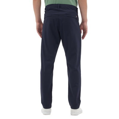 Mann mit einer Merinohose in navy mit Gesäßtaschen und weißen Sneakerschuhen. 