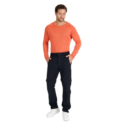 Mann mit einer schwarzen Merino Zip-Off Hose und einem orangenen Merino Langarmshirt. 