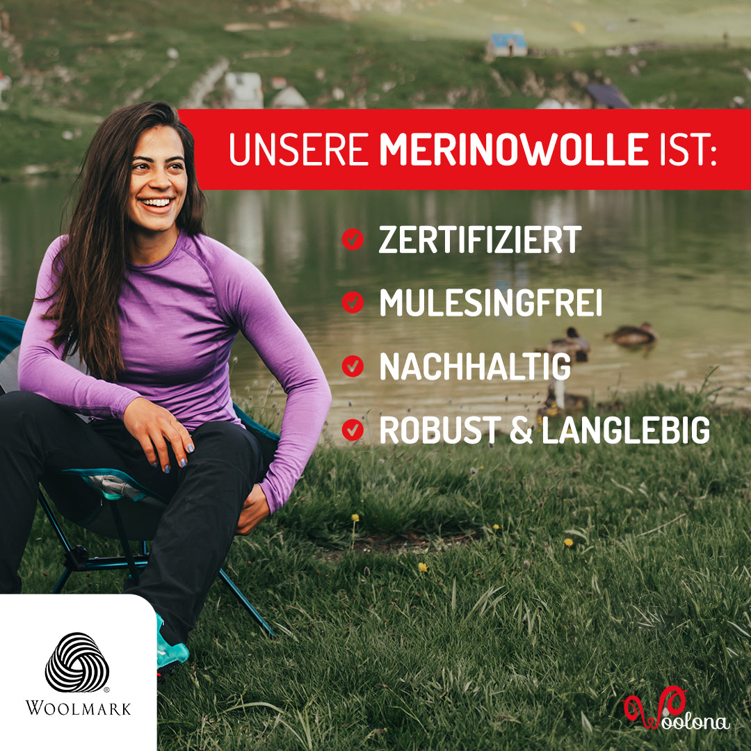 Frau sitzt auf einem Campingstuhl und trägt ein lilafarbenes Merino Langarmshirt.