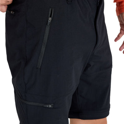 Mann in kurzer Variante der Zip-Off Merinohose mit Bein - und Hosentasche  mit Reißverschlüssen.