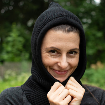 Die Dame trägt einen Kapuzenschal über dem Kopf bestehend aus 100% Merinowolle.