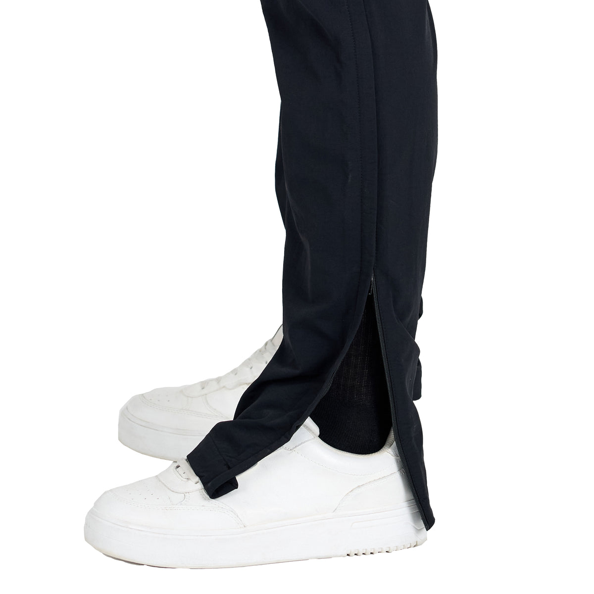 Detailfoto am Hosenbein einer Merino ZipOff Trekkinghose in der Farbe schwarz und weißen Schuhen. 
